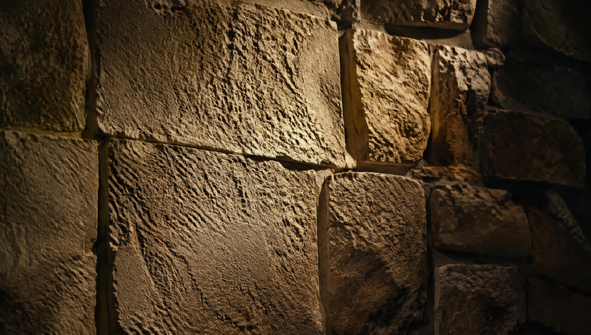 Mur en enduit minéral sculpté à la main imitant la pierre de taille, éclairage rasant